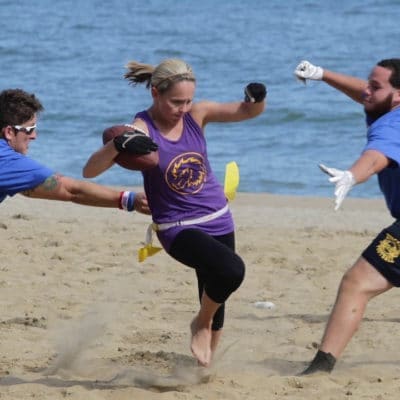 "Mensen spelen Flag Football op het strand, genietend van teamwork en plezier in de buitenlucht