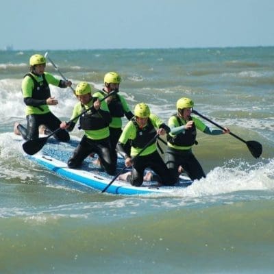 Mensen genieten van Mega Suppen op zee, samen op een XL surfplank voor een geweldige teamervaring