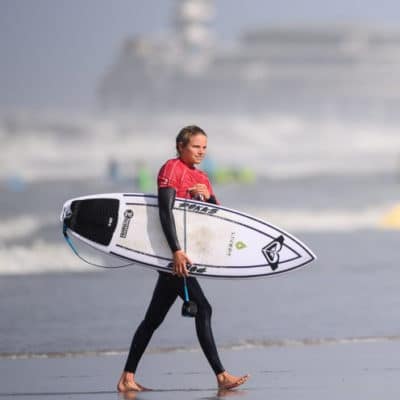 Vrouw met surfbord op het strand, perfect voor bedrijfsuitjes en strandactiviteiten voor teambuilding