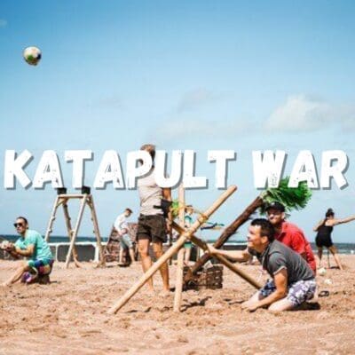 Mensen schieten een katapult vanaf het strand tijdens Katapult War on the Beach, vol actie en teamwork