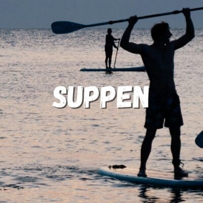 Man staat op een Stand Up Paddle Board en peddelt op de zee, genietend van het suppen op het wate