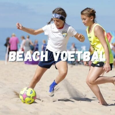 Mensen spelen beachvoetbal op het strand, omringd door zand en de zee, terwijl ze genieten van een leuke en actieve dag